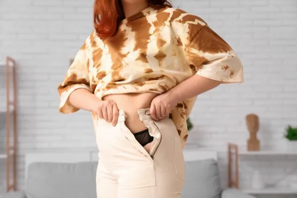 Image of woman trying to do her trousers up after pregnancy weight gain Stoke upon Trent